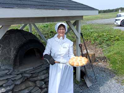 Costumed Lady removing buns
        from oven